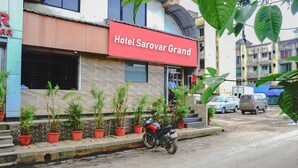 Hotel Sarovar Grand with a red sign, potted plants, a motorcycle, and parked cars. - Hotel Sarovar Grand (Panvel)