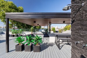 An outdoor patio with a covered seating area, potted plants, and a view of the cityscape. - [NEW!!] Astonishing Palermo Soho Home With Private Jacuzzi and Terrace (Palermo)