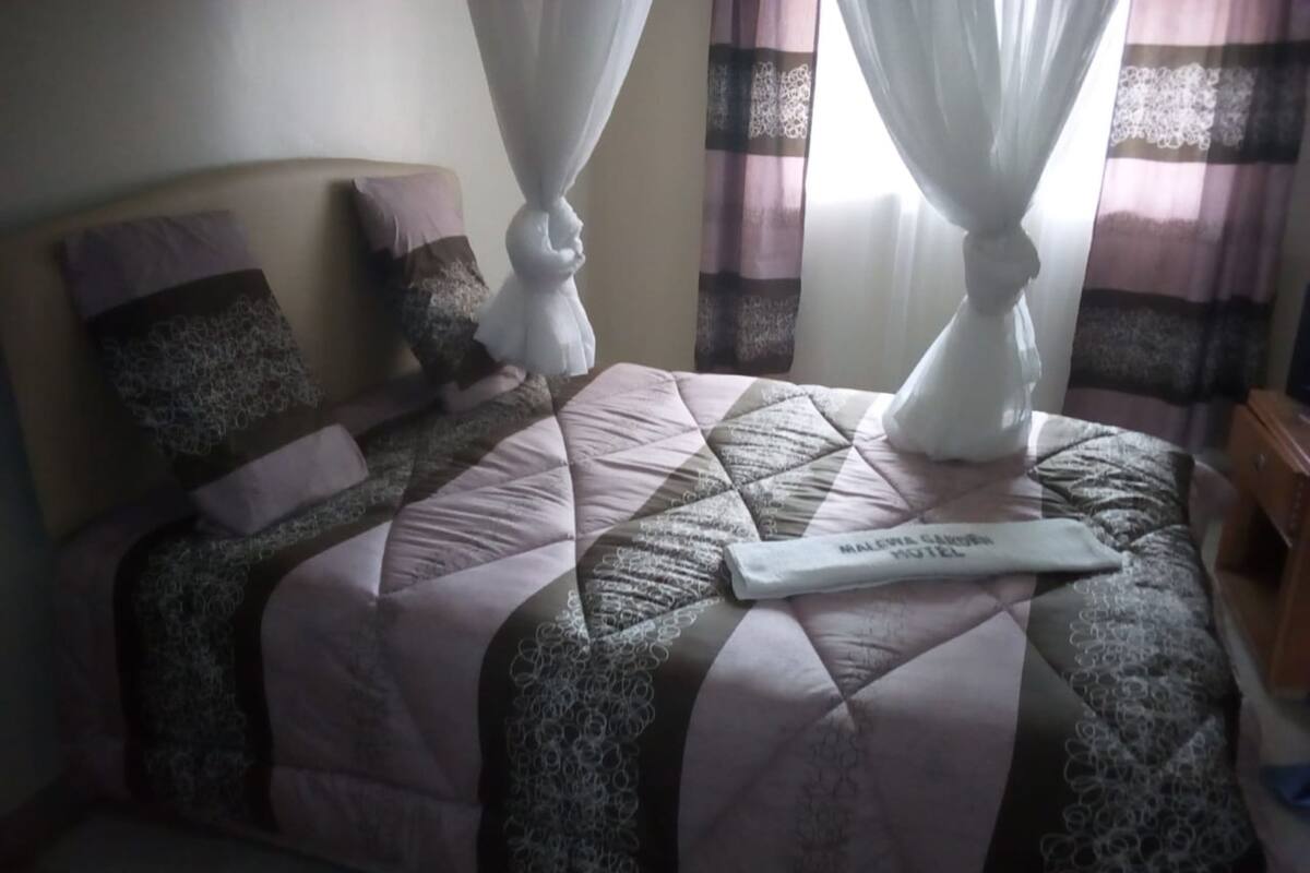 A bed with a quilted bedspread, two pillows, and a decorative headboard.