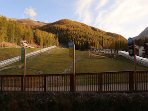Ein Skigebiet mit Seilbahn, Hinweisschild des Skiclubs und Bergelandschaft im Hintergrund.