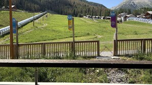A view of a mountainous area with a train track, wooden fences, and a clear sky.