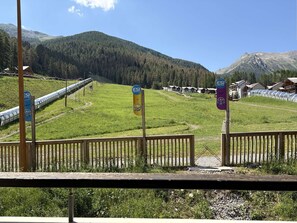 A view of a mountainous area with a train track, wooden fences, and a clear sky.