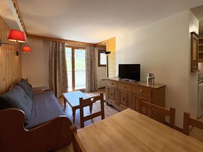A cozy room with a wooden dining table, a sofa, and a television. - Ski-in/Ski-out, Pool, Sauna, WiFi, Southern Exposure, Sleeps 6 - Les Orres 1800 (Les Orres)