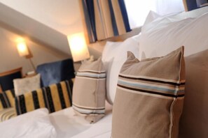 A hotel room with a neatly made bed, striped pillows, and a headboard. - Apartmenthaus Triton (Cologne)