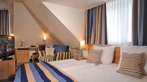A hotel room with a large bed, a TV, a desk, and a chair. - Apartmenthaus Triton (Cologne)