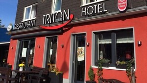 A hotel with a red facade, a visible restaurant sign, and multiple windows. - Apartmenthaus Triton (Cologne)