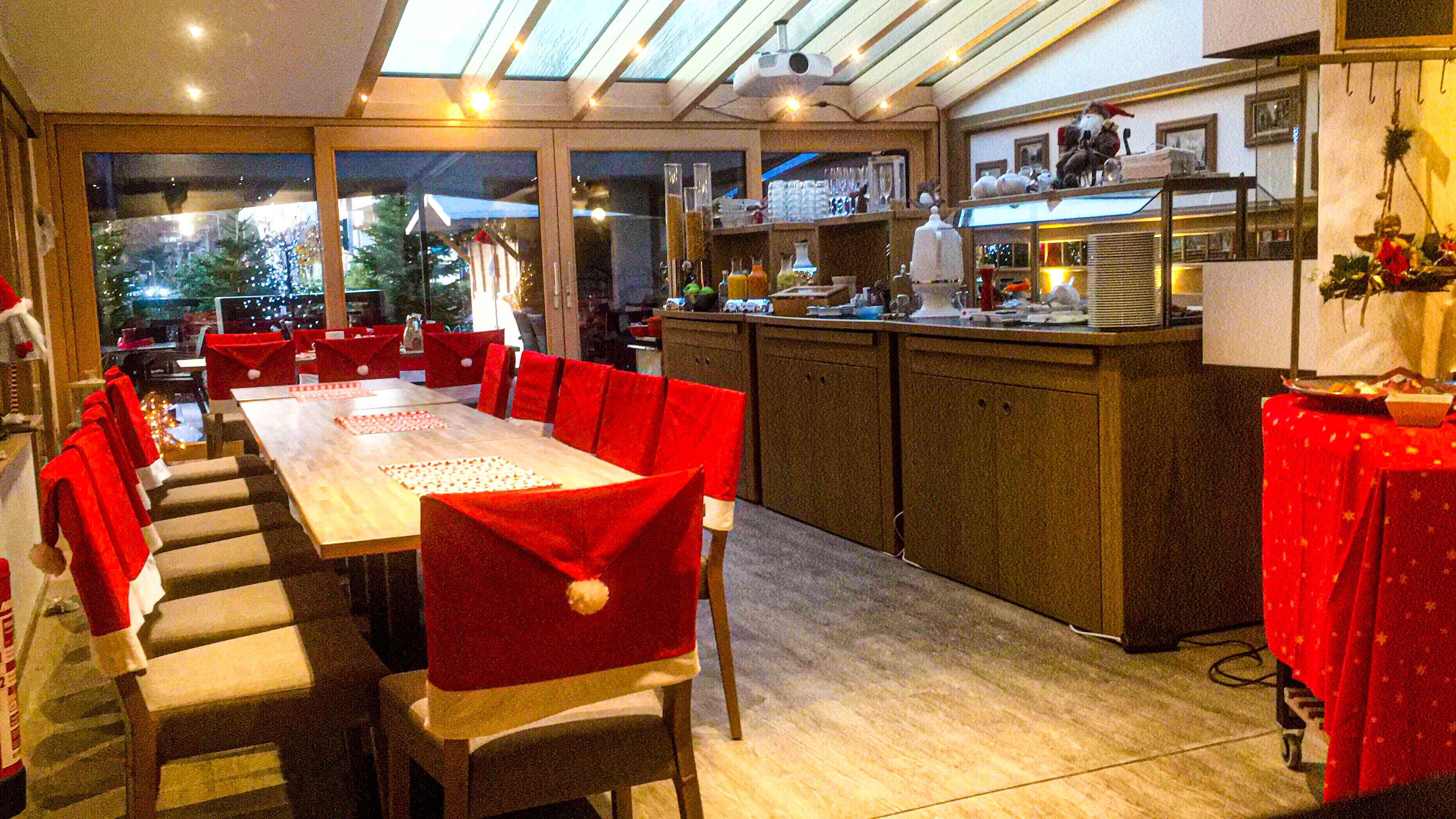 A modern kitchen with a large island, red chairs, and a dining area with a long table.