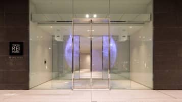The entrance to Tokyo REI Hotel with a modern glass facade and a sign indicating the hotel name.
