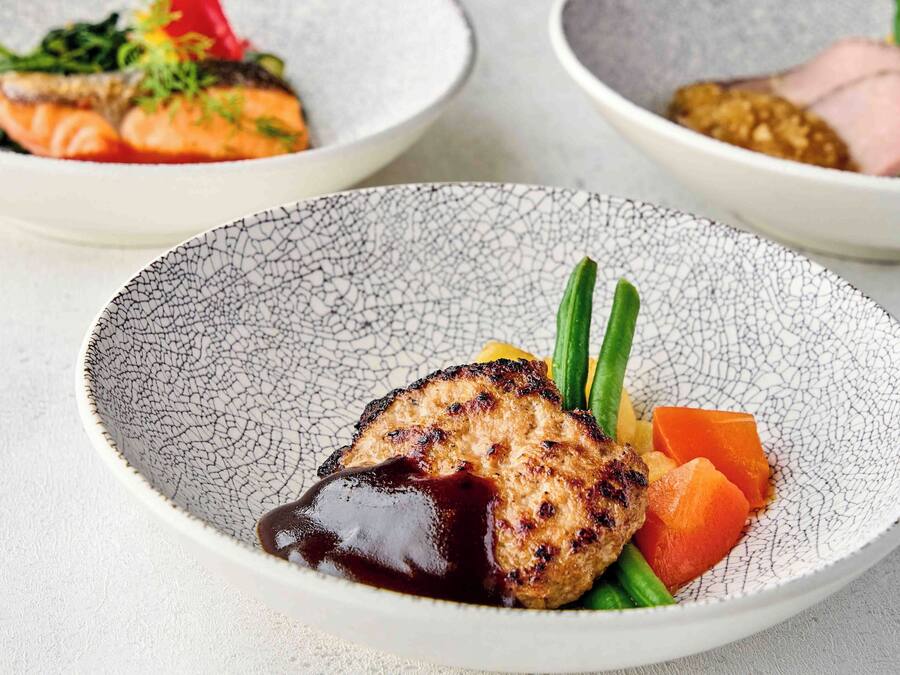 A plate with grilled meat, vegetables, and sauce.