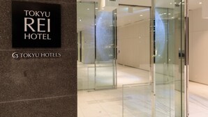 Een moderne hotelentree met een glazen deur en een bord waarop 