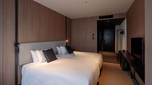 Een hotelkamer met twee bedden, een flatscreen televisie en een bureau.