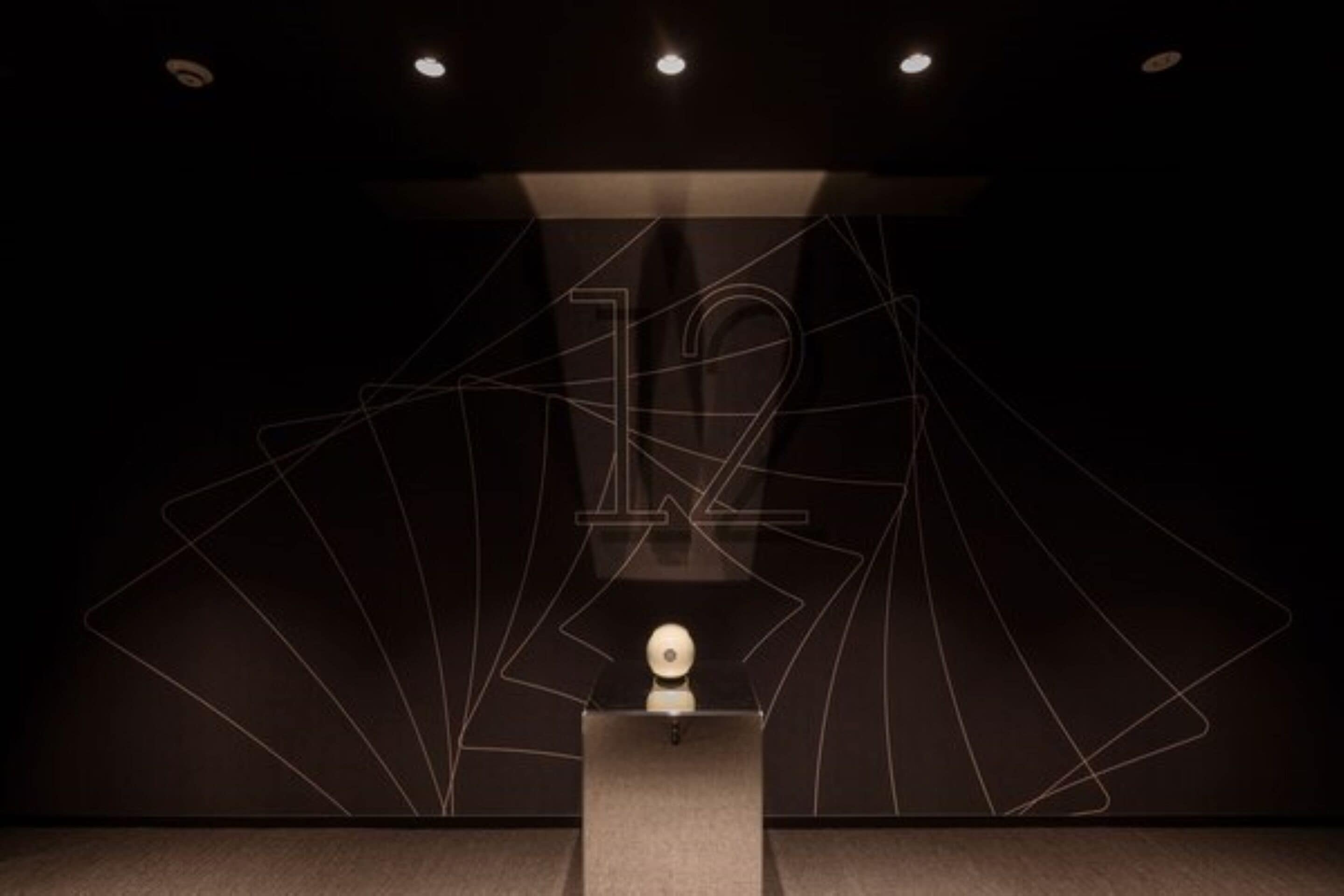 A dark room with a podium and a light sculpture.