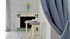 A room with a marble floor, a fireplace with a vase of flowers, and a table with candles. - Luxury Rome Guest House (Rome)