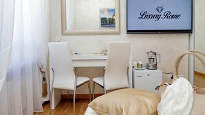 A hotel room with a bed, a desk, two chairs, a coffee maker, and a TV displaying "Luxury Rome". - Luxury Rome Guest House (Rome)