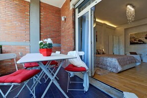 A modern room with a brick wall, a sliding glass door leading to a bedroom, a dining table with red cushions, and a potted plant. - Luxury Rome Guest House (Rome)