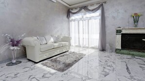 A modern living room with a white sofa, a marble floor, and a fireplace. - Luxury Rome Guest House (Rome)