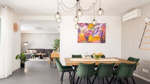 Un espace repas moderne avec une table en bois, des chaises vertes et des luminaires suspendus.