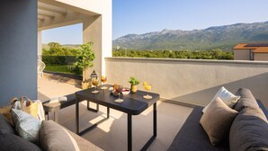 Une terrasse sur le toit avec une table dressée pour deux personnes, un canapé et une vue sur les montagnes.