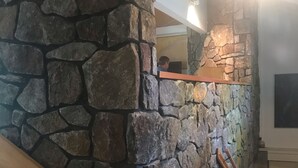 A stone wall with a wooden staircase and a wooden handrail.