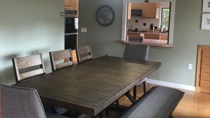 A dining room with a large wooden table, grey upholstered chairs, and a pendant light.