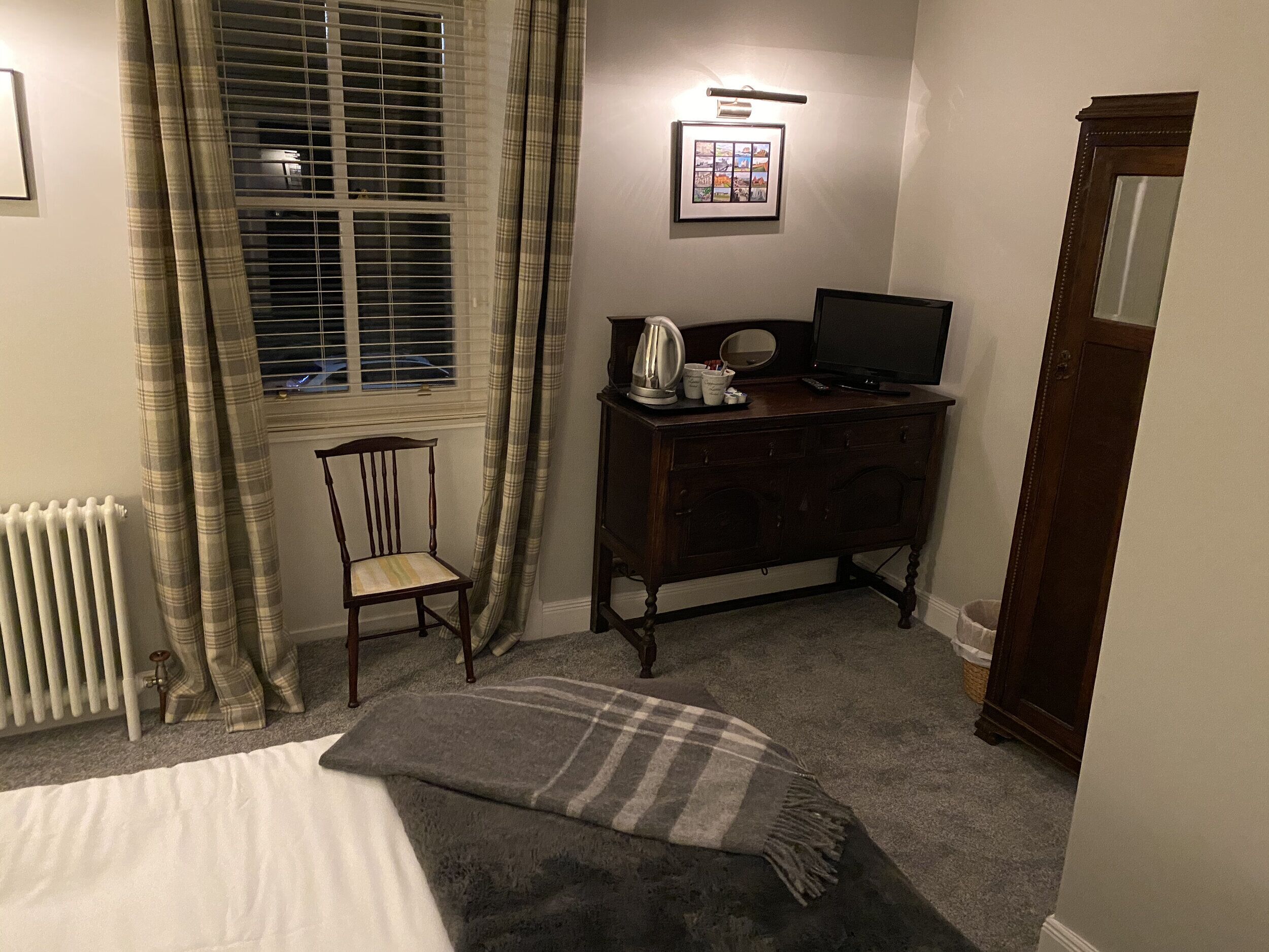 Une chambre à coucher comprenant un lit, une chaise, une commode, un téléviseur et un radiateur.