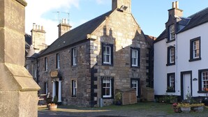 A stone building with a traditional design, featuring a prominent entrance and a small porch area with potted plants. - The Covenanter Hotel (Cupar)