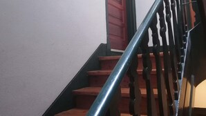 Una escalera de madera con barandilla de metal que conduce a una puerta roja.