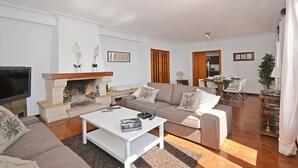 Una sala de estar con chimenea, sofá, mesa de centro y comedor.