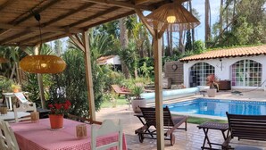 Un espace extérieur abrité comprenant une piscine, des tables recouvertes de nappes à carreaux et des chaises.