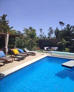 A swimming pool with lounge chairs and a pergola.