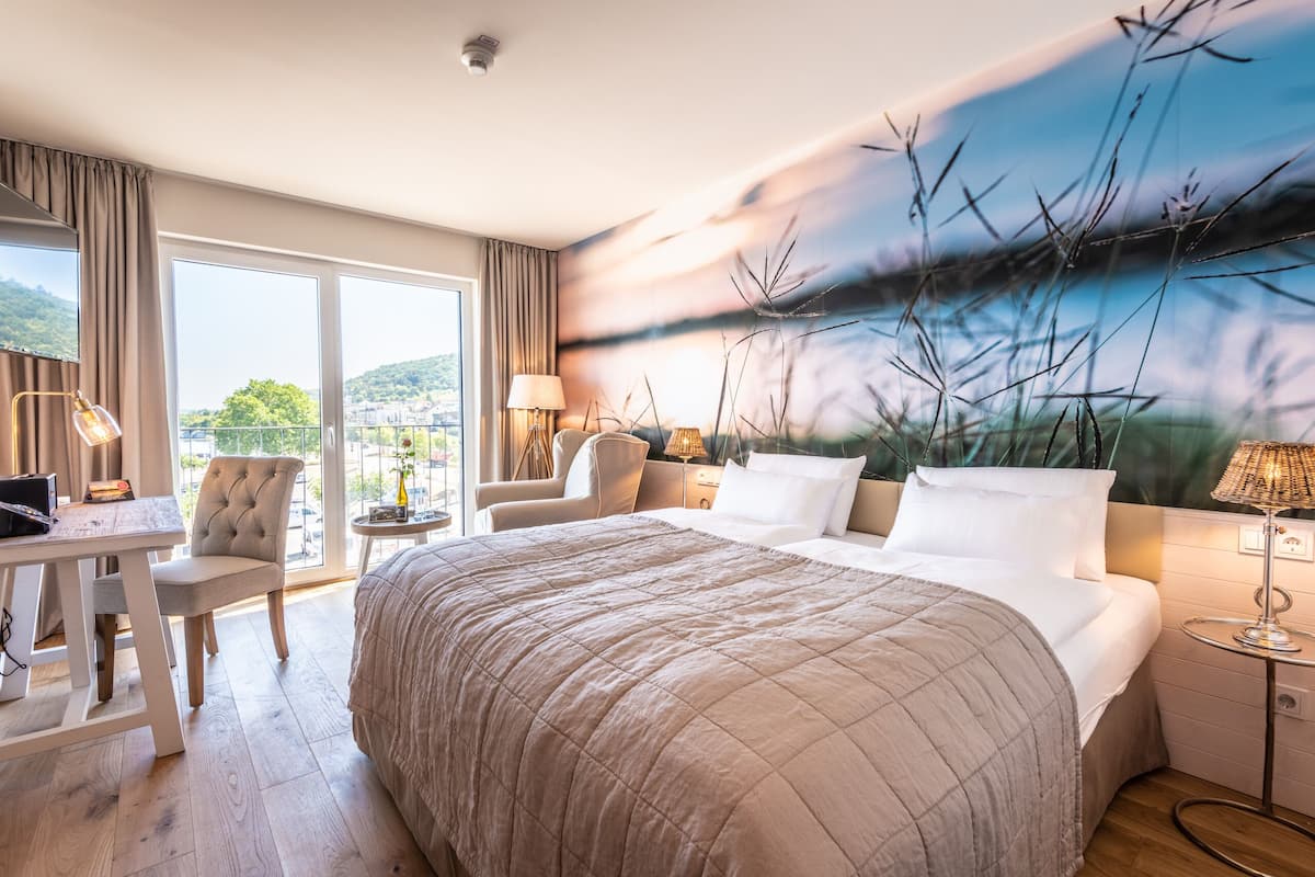 Une chambre d’hôtel avec un grand lit, un bureau, une chaise et une vue sur l’extérieur.