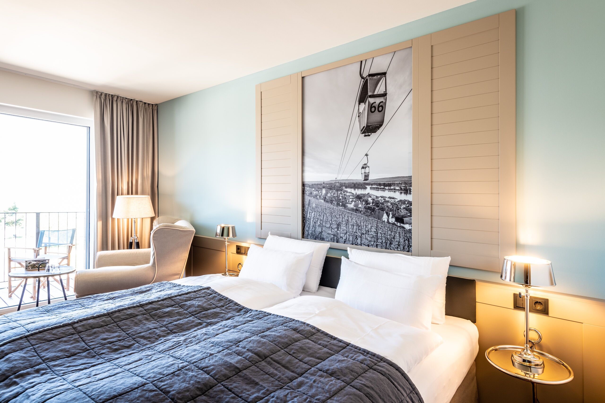 A hotel room with a large bed, a chair, a table, and a window with curtains.