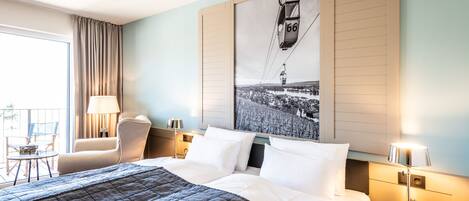A hotel room with a large bed, a chair, a table, and a window with curtains.