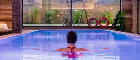 Una piscina interior con amplias ventanas que ofrecen vistas al exterior.