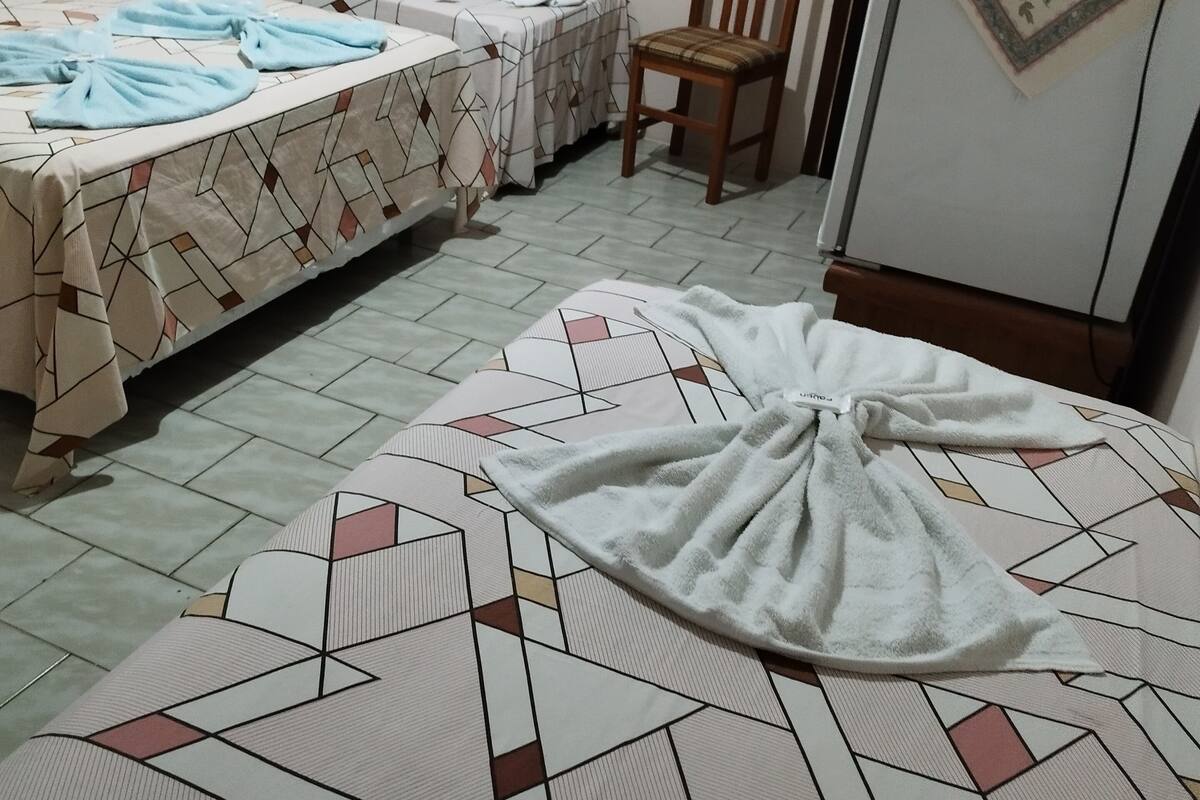 A hotel room with two beds, a chair, and a refrigerator.
