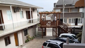 A parking area with several cars, a wooden pergola, and a building with multiple windows and balconies. - Hotel Santa Rita (Capao da Canoa)