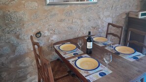 A rustic dining table set with plates, wine, and glasses, against a stone wall with a mirror above.