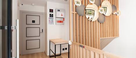A modern hotel lobby with a wooden partition, a small table, and a wall-mounted security camera.