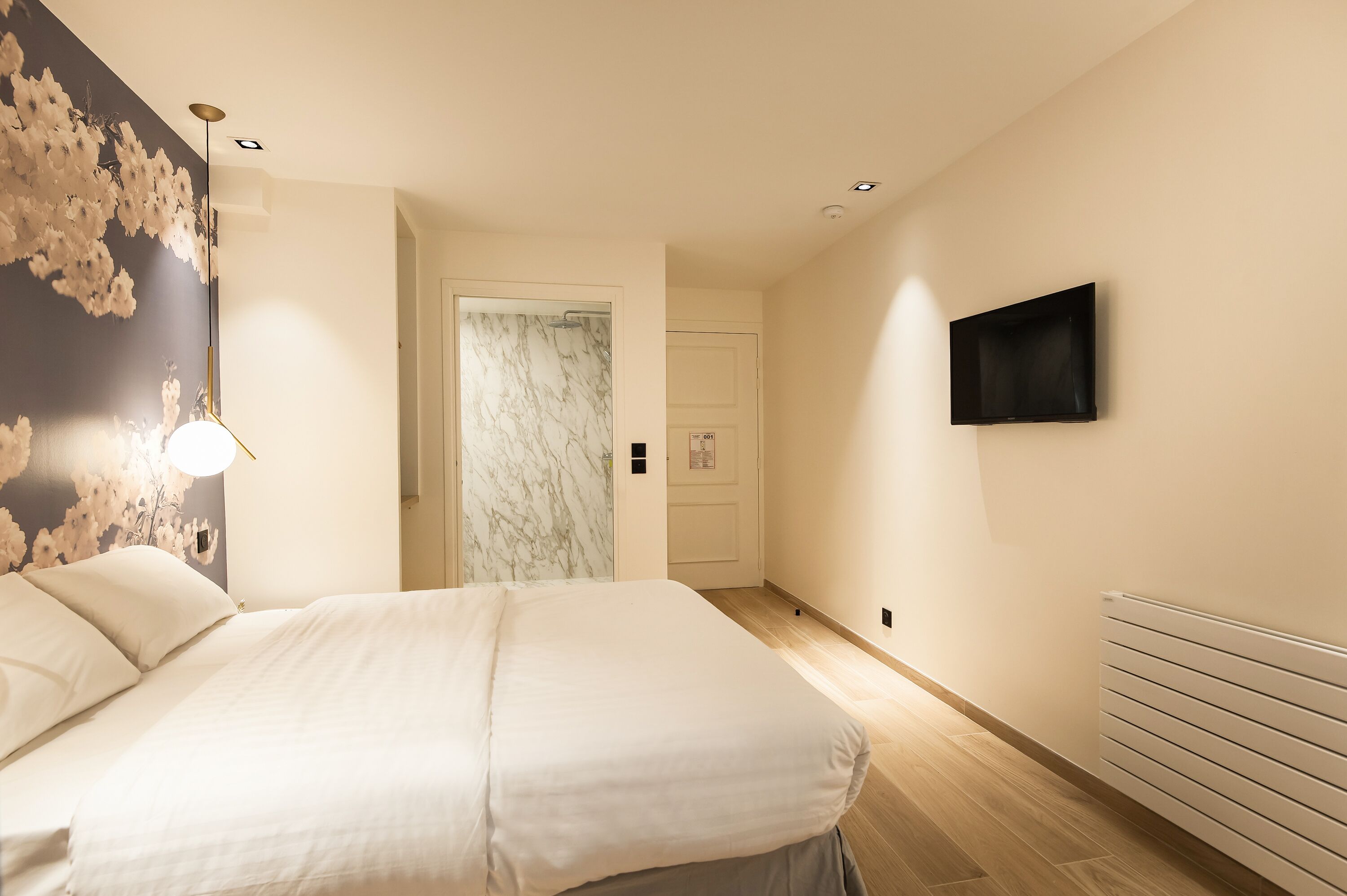 A bedroom with a bed, a wall-mounted TV, and a marble-patterned door.