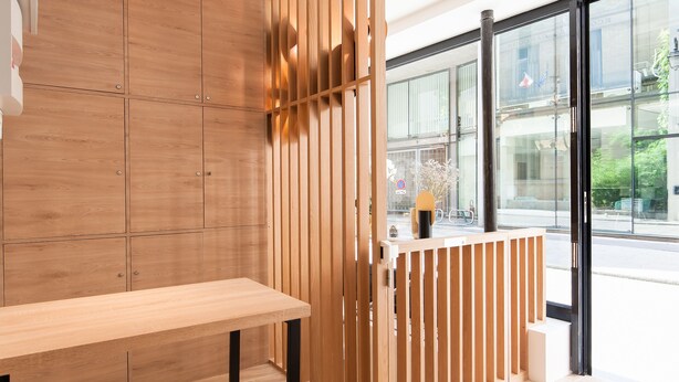 Un interior moderno con un panel de madera, un banco y vistas amplias a través de grandes ventanas.