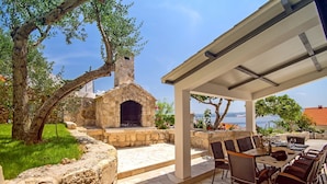 An outdoor patio with stone steps leading to a stone-built fireplace, surrounded by lush greenery and overlooking a scenic view. - Villa Dasianda - only 90 m from the beach, private 30msq heated pool (Stanici)
