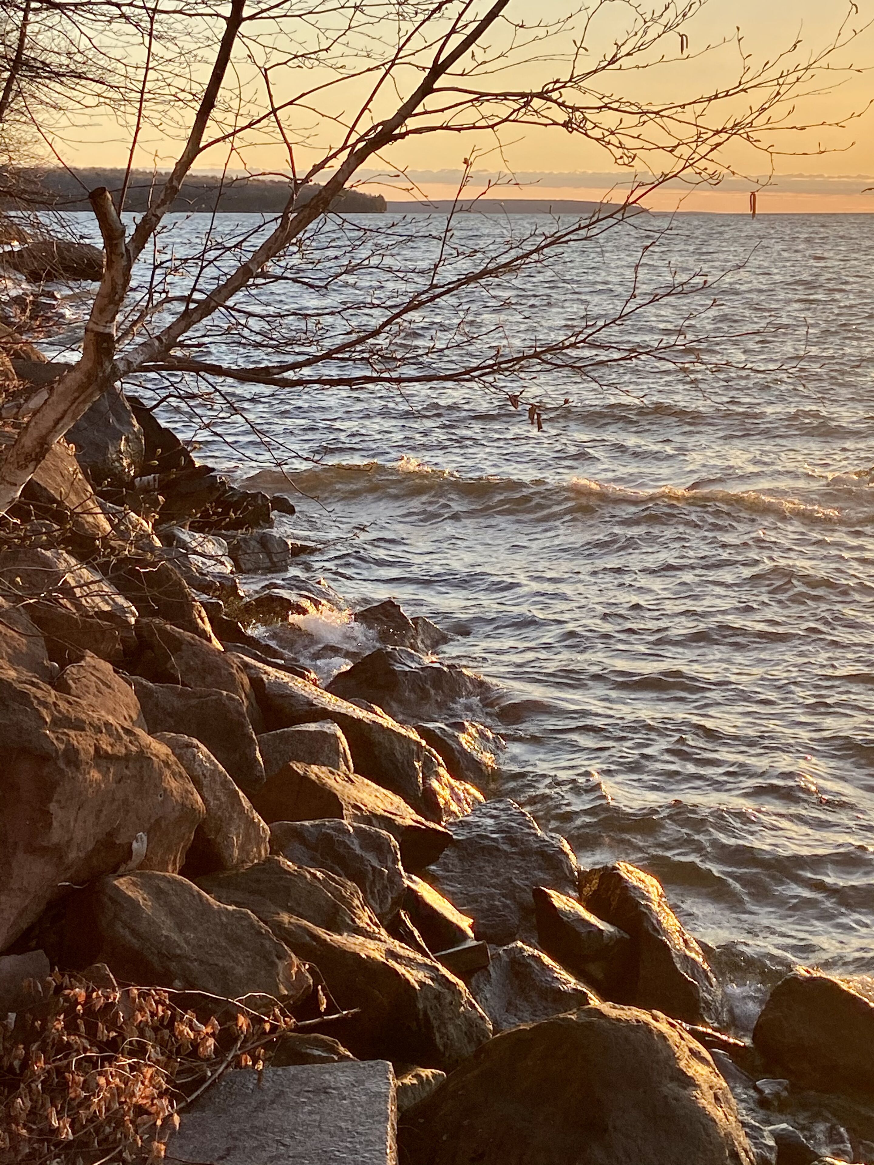 A rocky shoreline with waves at sunset.