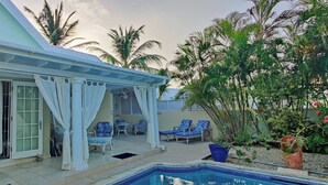 Ein Poolbereich mit überdachter Terrasse, Liegestühlen und Schwimmbecken.