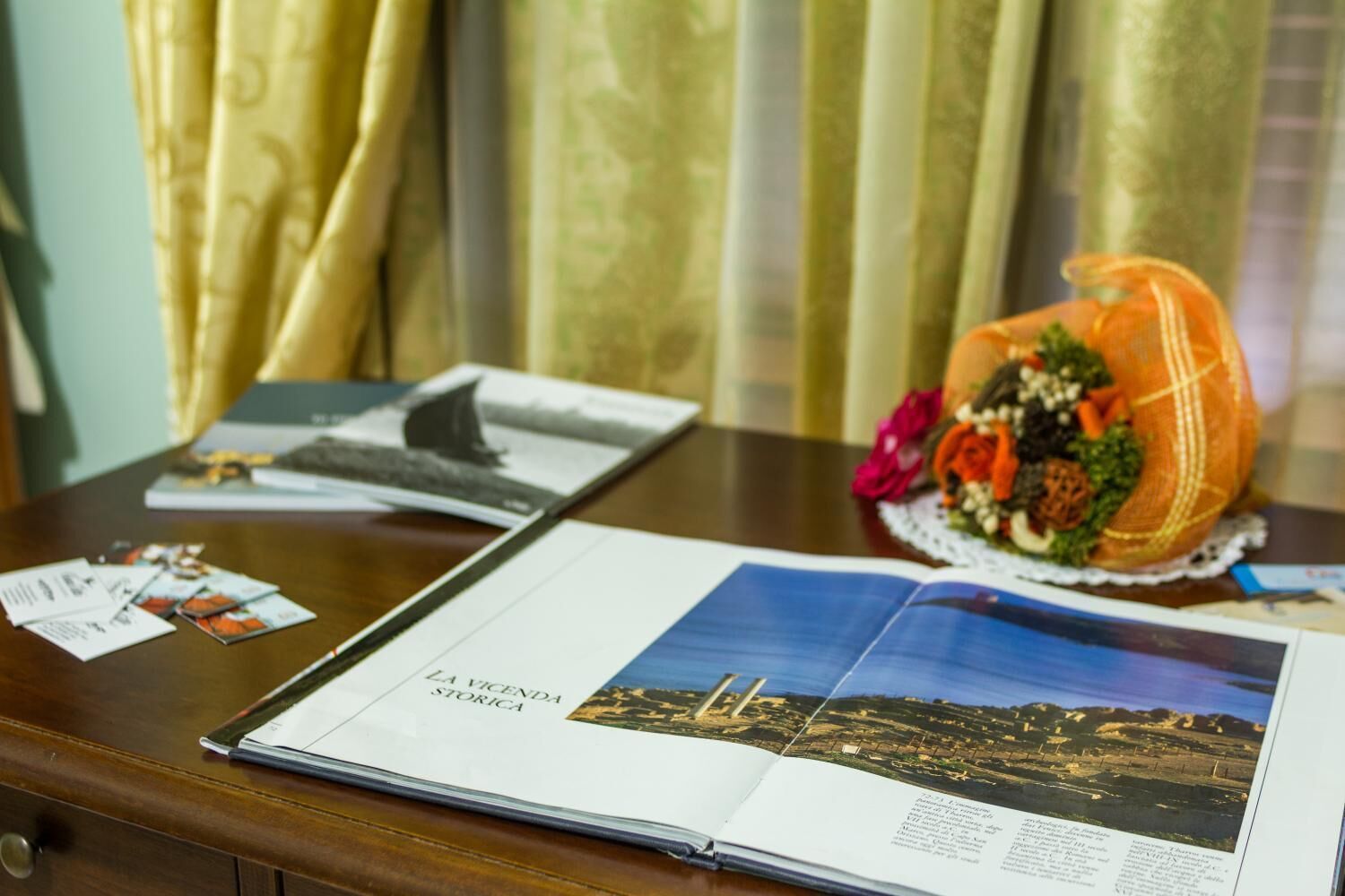 Een brochure op een houten tafel, met een decoratieve bloemenmand en een boek.