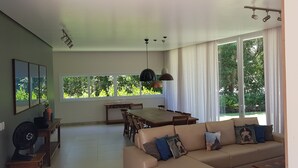 Ein geräumiges Wohnzimmer mit großem Fenster, einem Essbereich und einer Couch mit dekorativen Kissen.