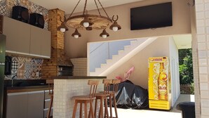 Eine Küche mit Kühlschrank, Holzschränken, einer Ziegelwand, einer Hängelampe und einer Treppe, die zu einem Balkon führt.