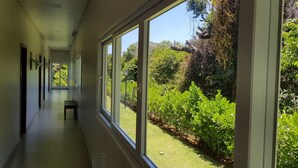 Ein Flur mit großen Fenstern, einer Bank und Blick auf einen Garten.