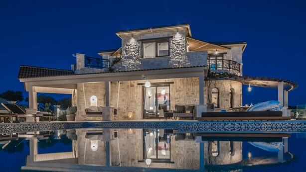 Ein luxuriöses Haus mit Schwimmbad, Steinmauern und Außenbereich mit Sitzgelegenheiten.
