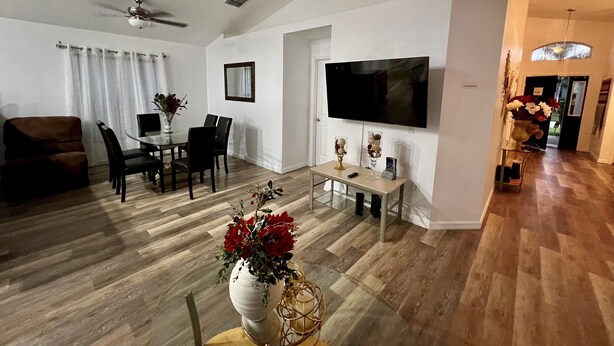 Un salon moderne comprenant un coin repas, un téléviseur à écran plat fixé au mur et un ventilateur de plafond.