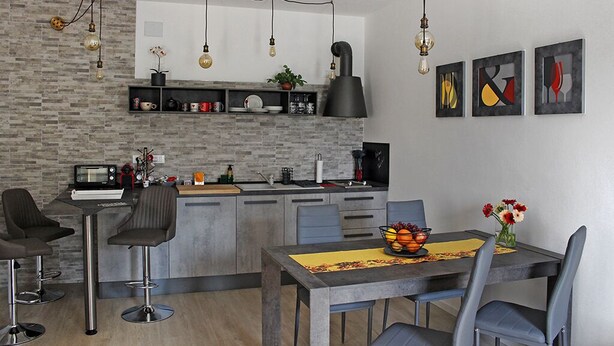 Una cocina moderna con salpicadero de ladrillo gris, electrodomésticos de acero inoxidable y una isla central con taburetes de bar.